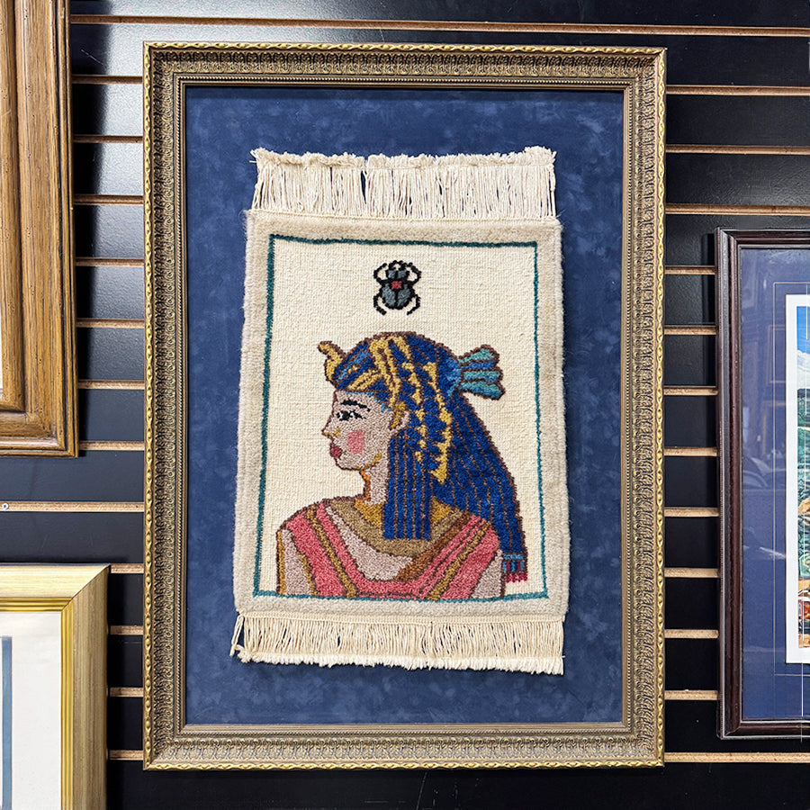 Framed Egyptian rug art depicting female with insect